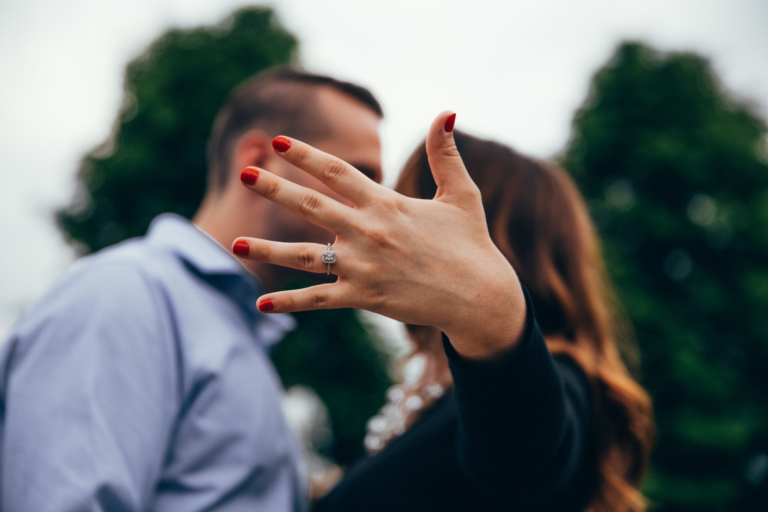 Woman holding up finger with engagement ring on it.